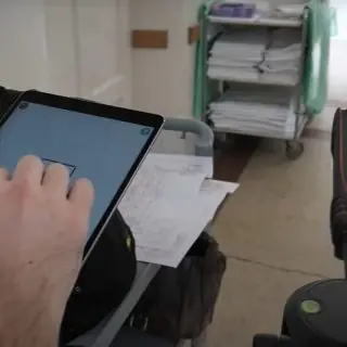Tablet zur digitalen Gebäudedokumentation mit Rollwagen und Krankenhausbetten im Hintergrund