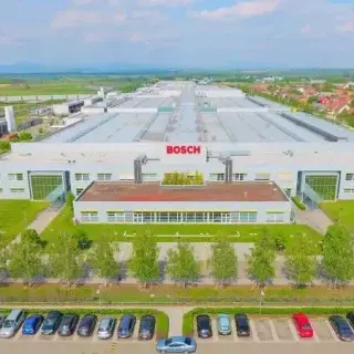 Moderne BOSCH-Industrieanlage in Ungarn mit großer Parkplatzfläche und grüner Umgebung.